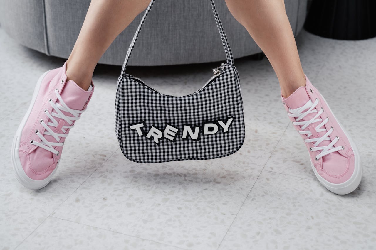 Pink sneakers paired with a trendy checked bag indoors, showcasing youthful fashion.